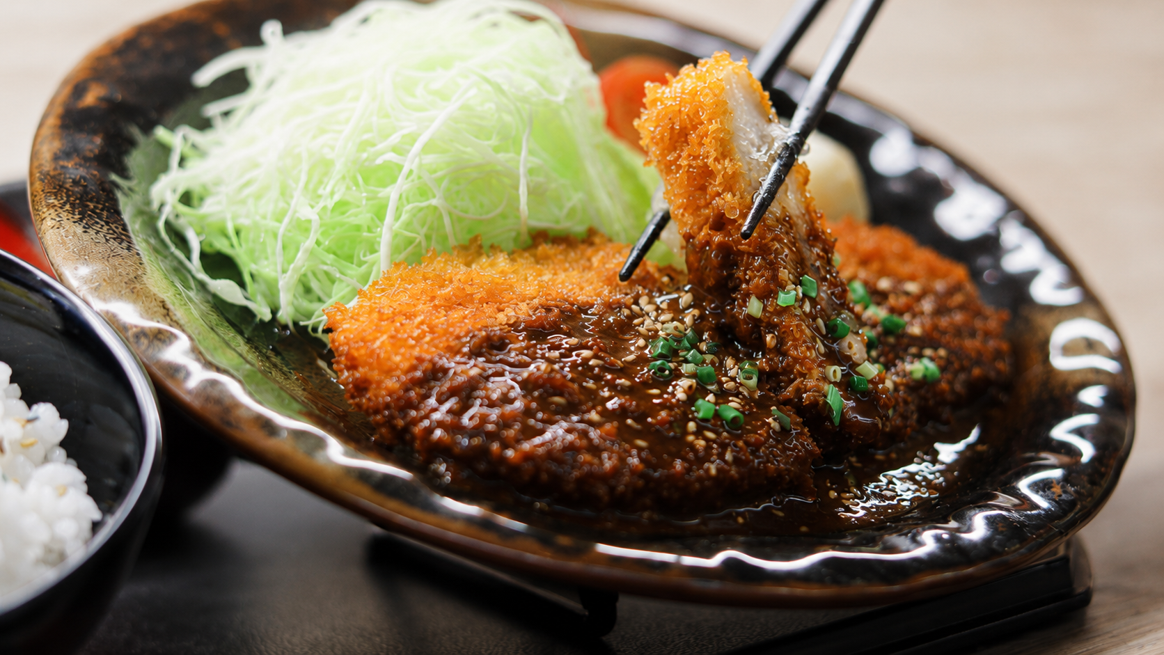 Close-up of a hand-painted miso katsu Japanese food replica with chopsticks lifting a glossy slice