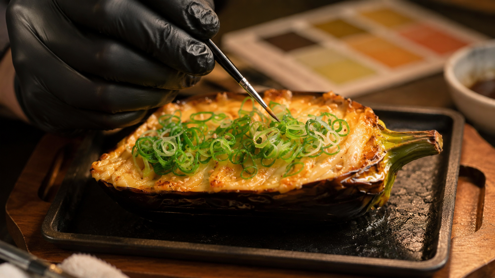A gloved artisan hand-painting scallion detail onto a custom food replica with a fine brush and pigment palette